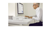 cpa sign on desk, computer monitor, and man typing on keyboard